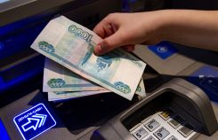 Посетитель кладет деньги на банковский счет в банкомате