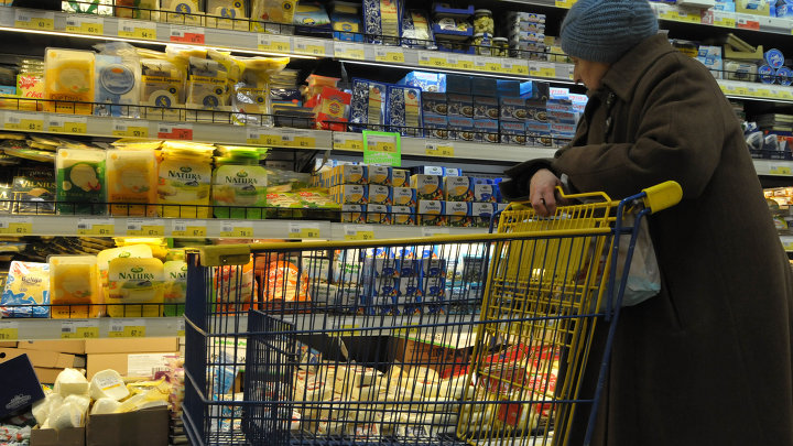 Пожилая женщина выбирает сыр в супермаркете